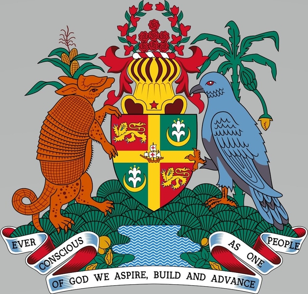Grenada’s coat of arms shows Grand Etang Lake, a crater lake on the volcano that formed Grenada. In the center of the shield is Christopher Columbus’s ship, the Santa Maria, which landed on the island in 1498. The gold cross dividing the shield, the two Madonna lilies, and the national motto signal the importance of religion. Two lions symbolize past UK rule (1762-1974), as well as Grenada’s current status as a Commonwealth country. The corn stalk and banana plant represent agriculture. The armadillo and Grenada dove next to the shield are native to the island, and the roses in the bougainvillea flower garland represent Grenada’s seven communities.