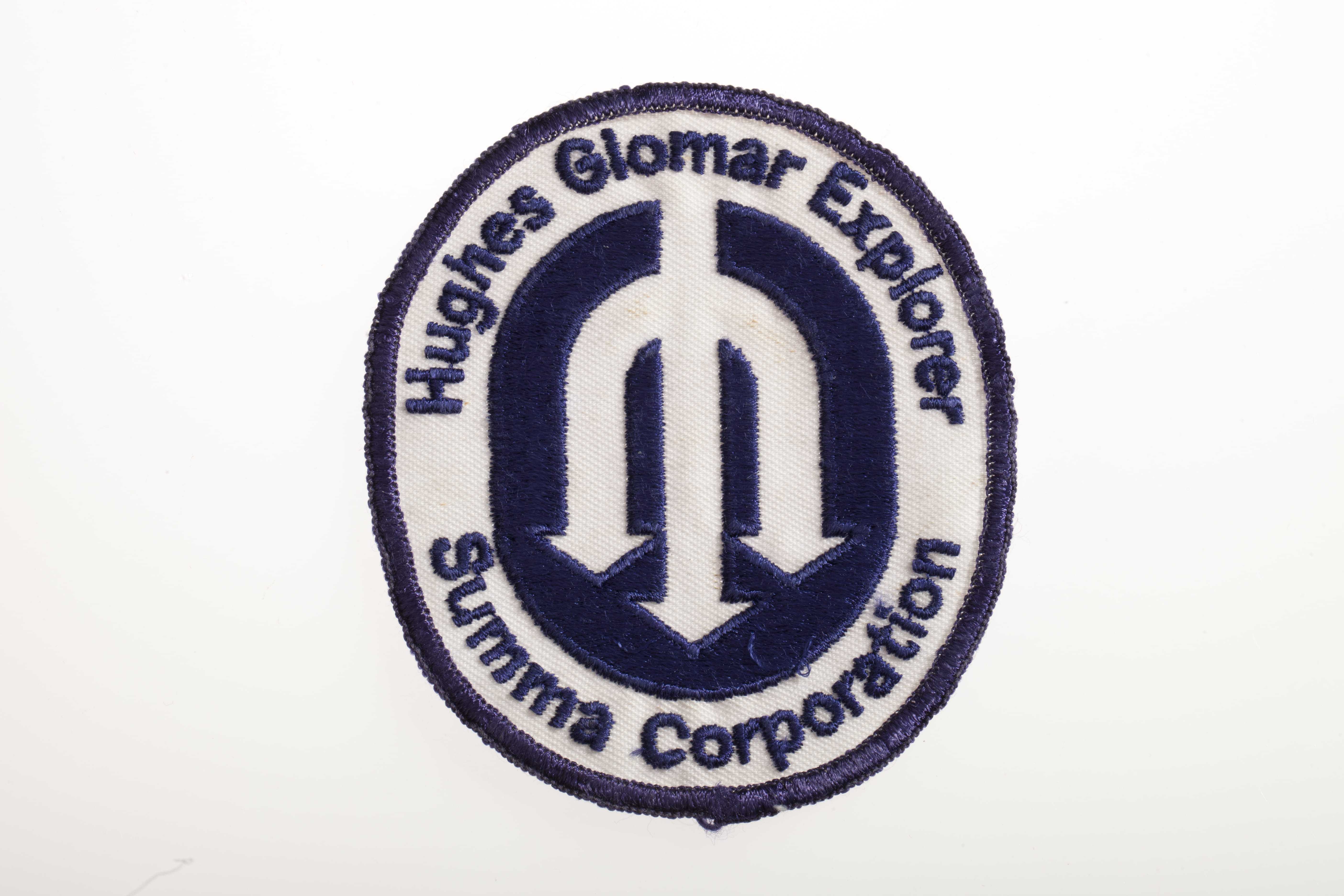 A patch with three divergent arrows pointing down and the words "Hughes Glomar Explorer Summa Corporation."