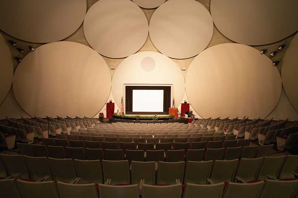 The theater inside the CIA Headquarters Auditorium, complete with a stage and large white disks to amplify sound.