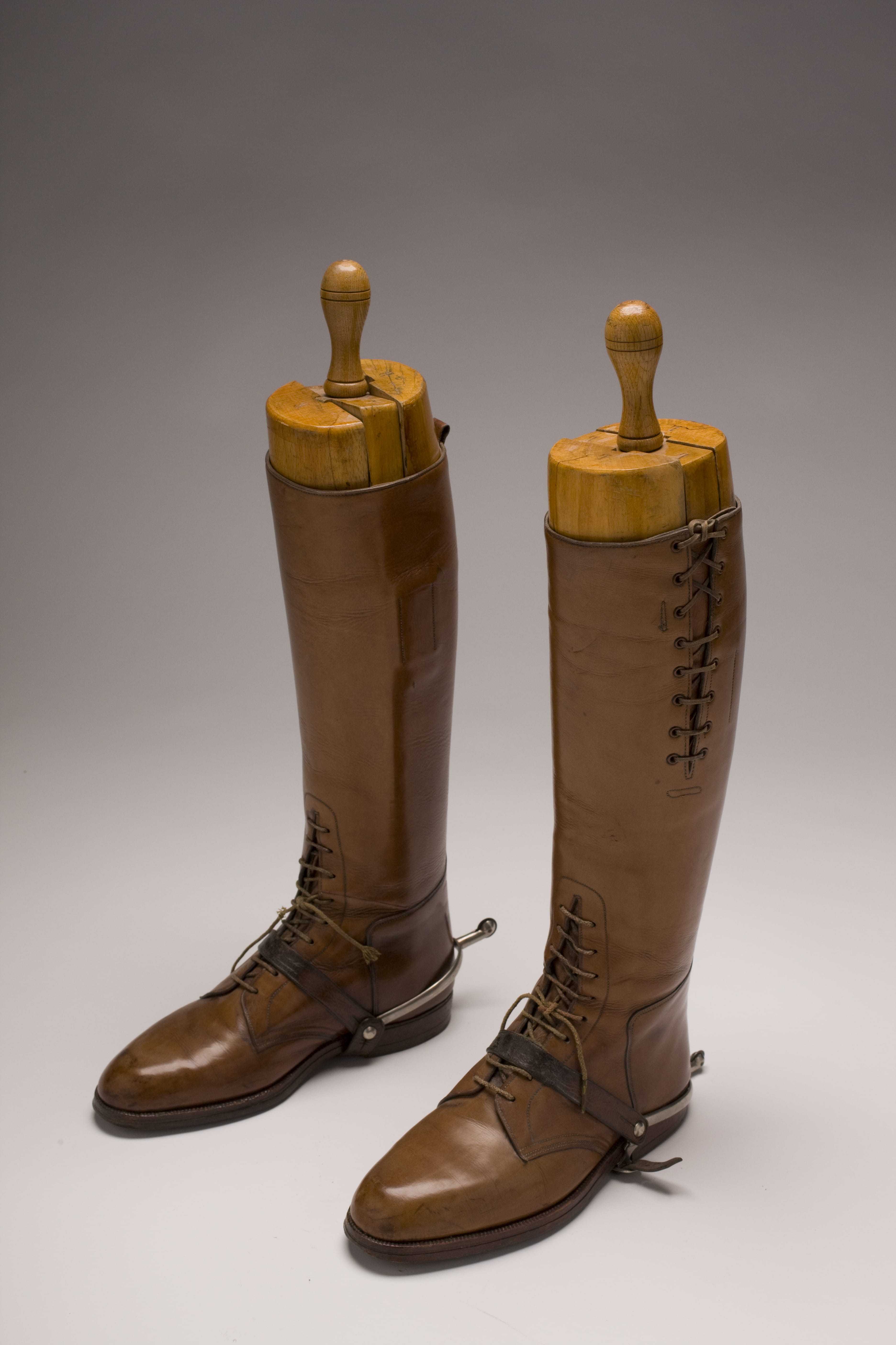 Tall brown leather boots with laces on the front and sides
