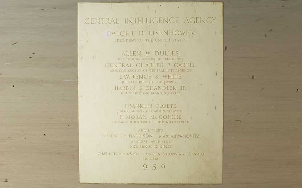 A rectangular, white, marble, cornerstone engraved with the names of officials responsible for creating the first CIA Headquarters Building.