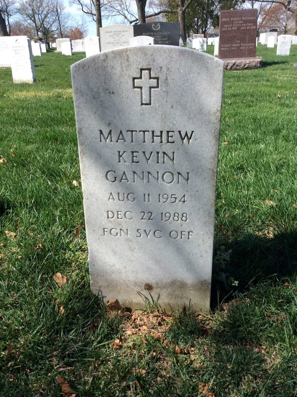 A close up of a tombstone in a semetary inscribed with his name, "Matthew Kevin Gannon," under a cross.