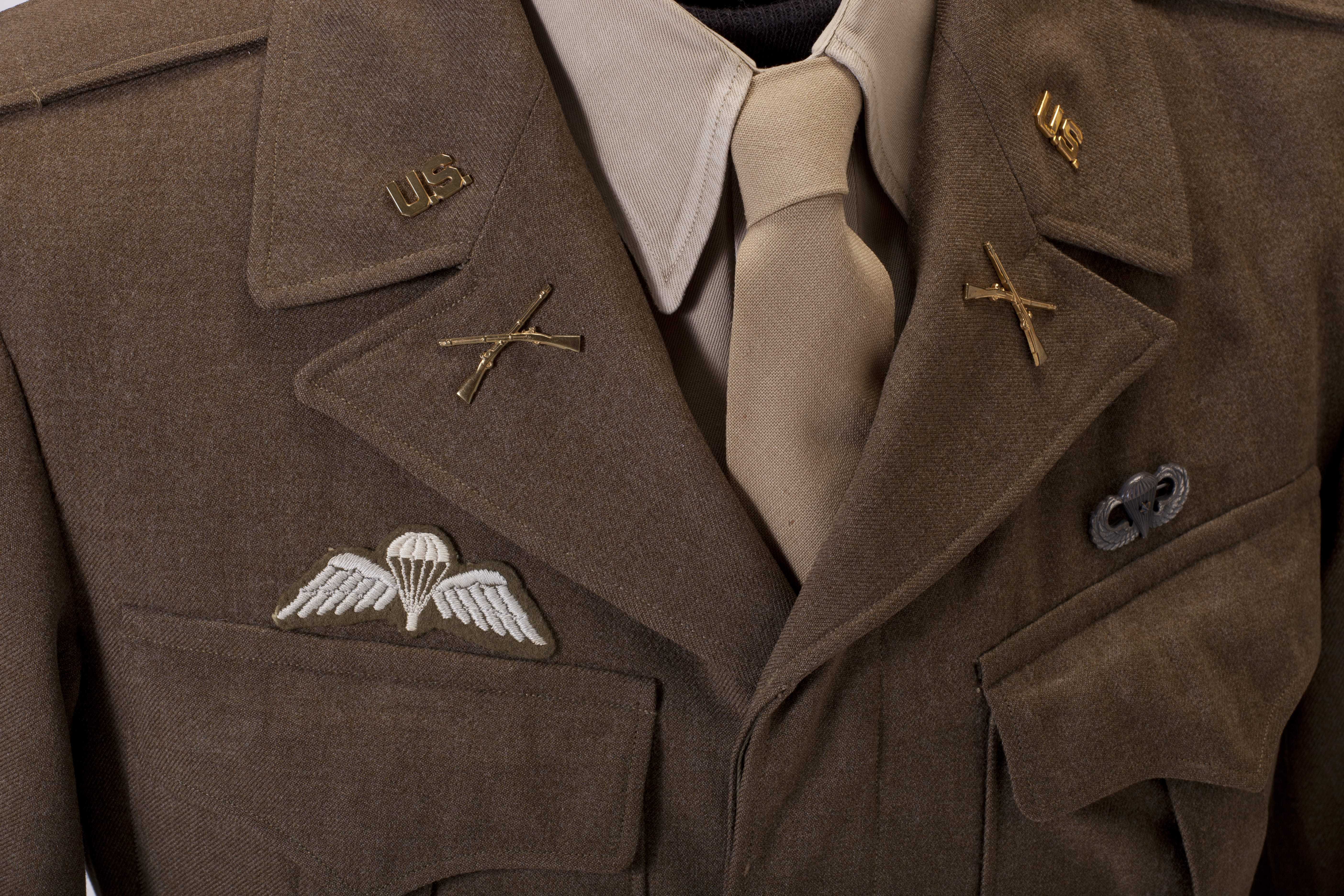 A close up view of a brown Colonel uniform jacket with pins on the lapel and above the breast pockets.