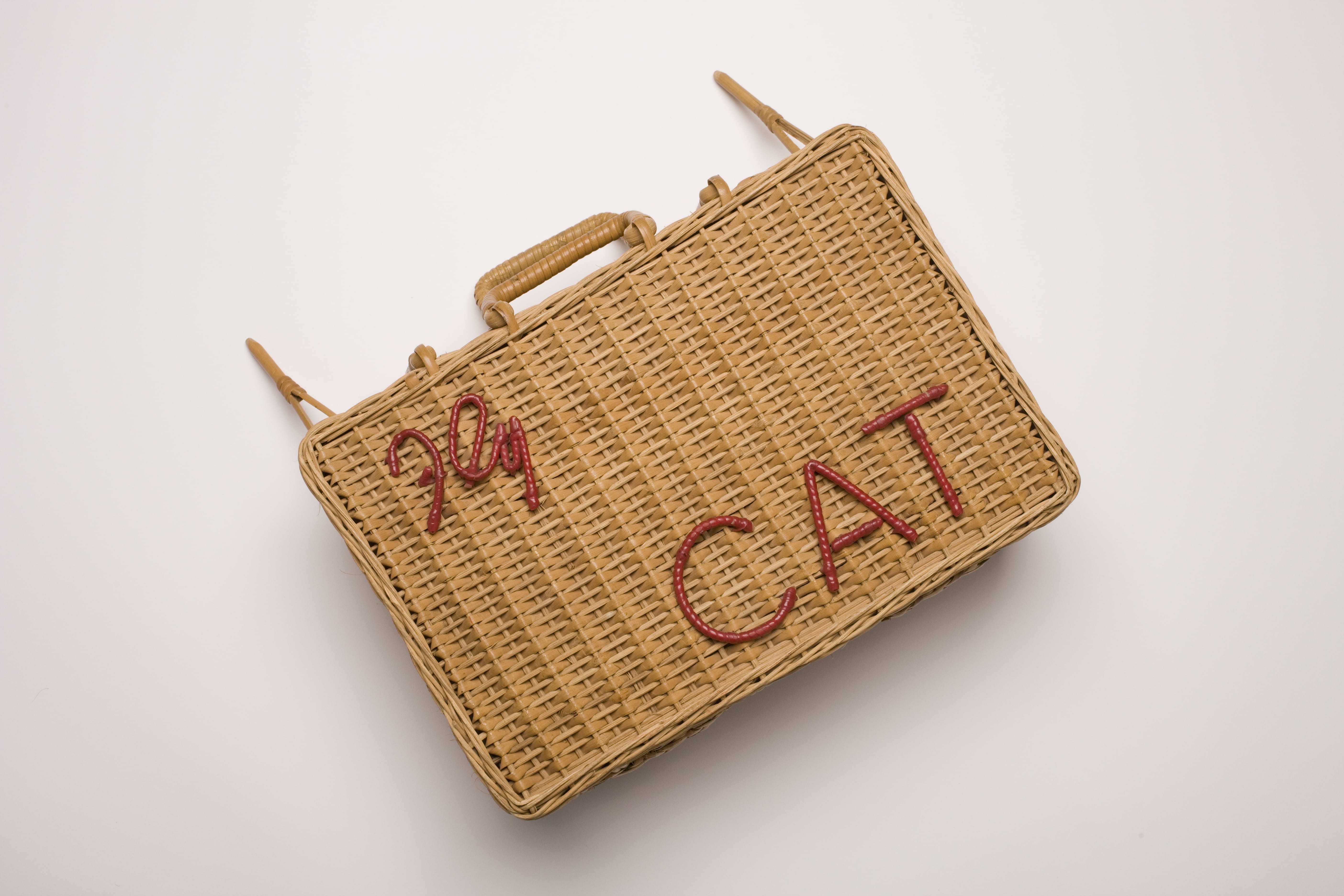 A wicker basket with the phrase "fly CAT" woven in red on the front
