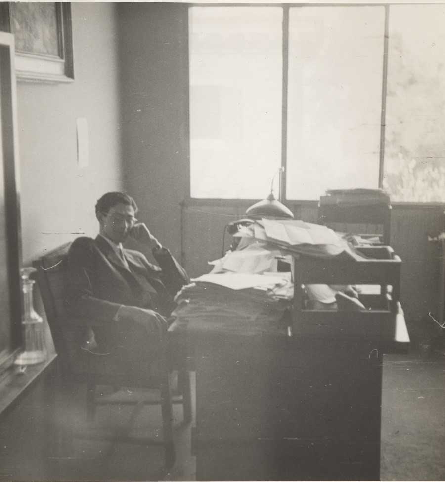 James Angleton sitting in his OSS office with his head resting on his hand.