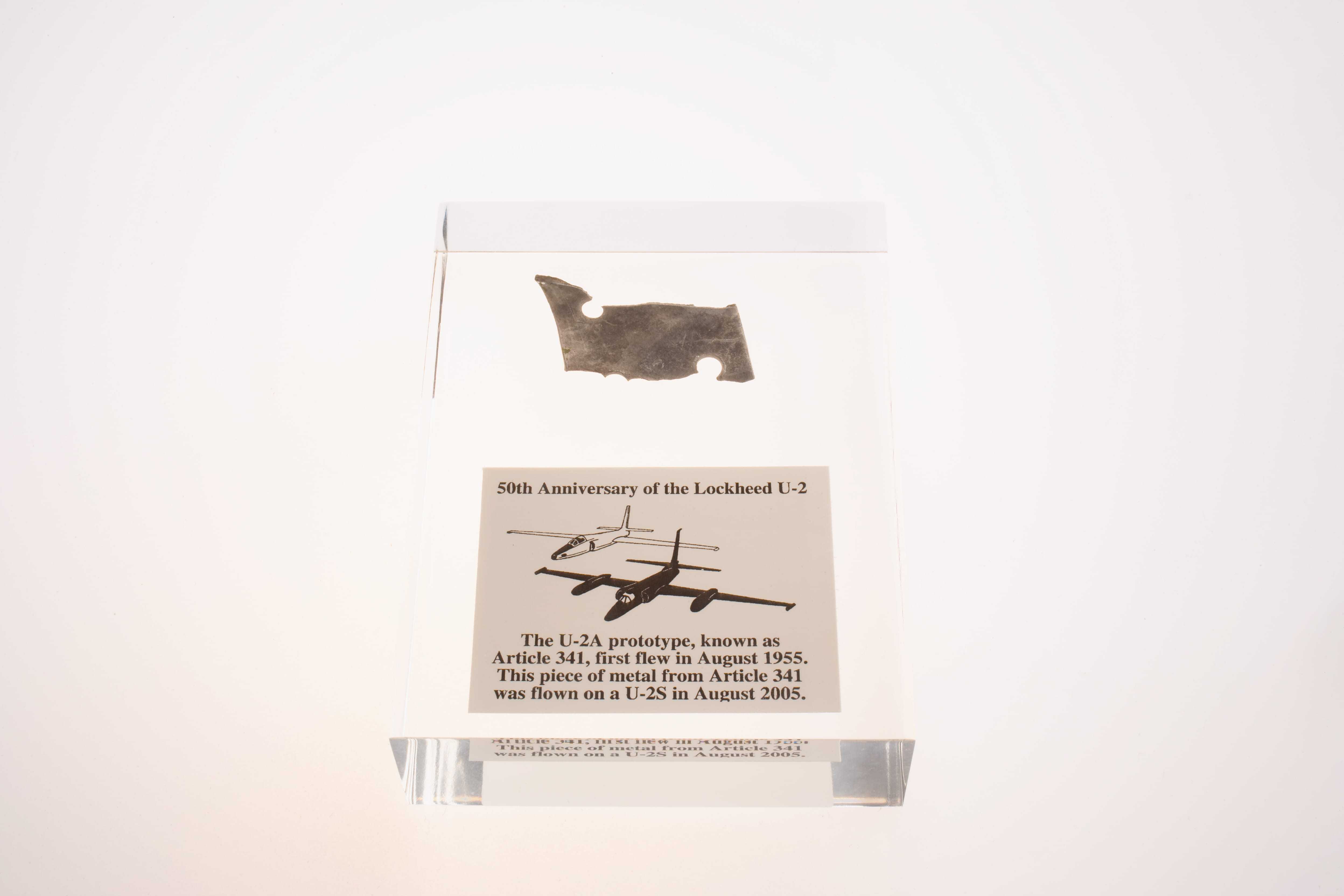 A metal shard from the U-2's first official flight encased in Lucite along with a plaque describing the event