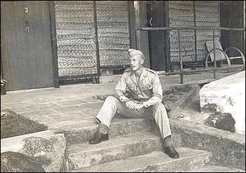 A black and white photograph of Dr. Christian Lambertsen in an OSS Maritime Unit uniform sitting on steps.