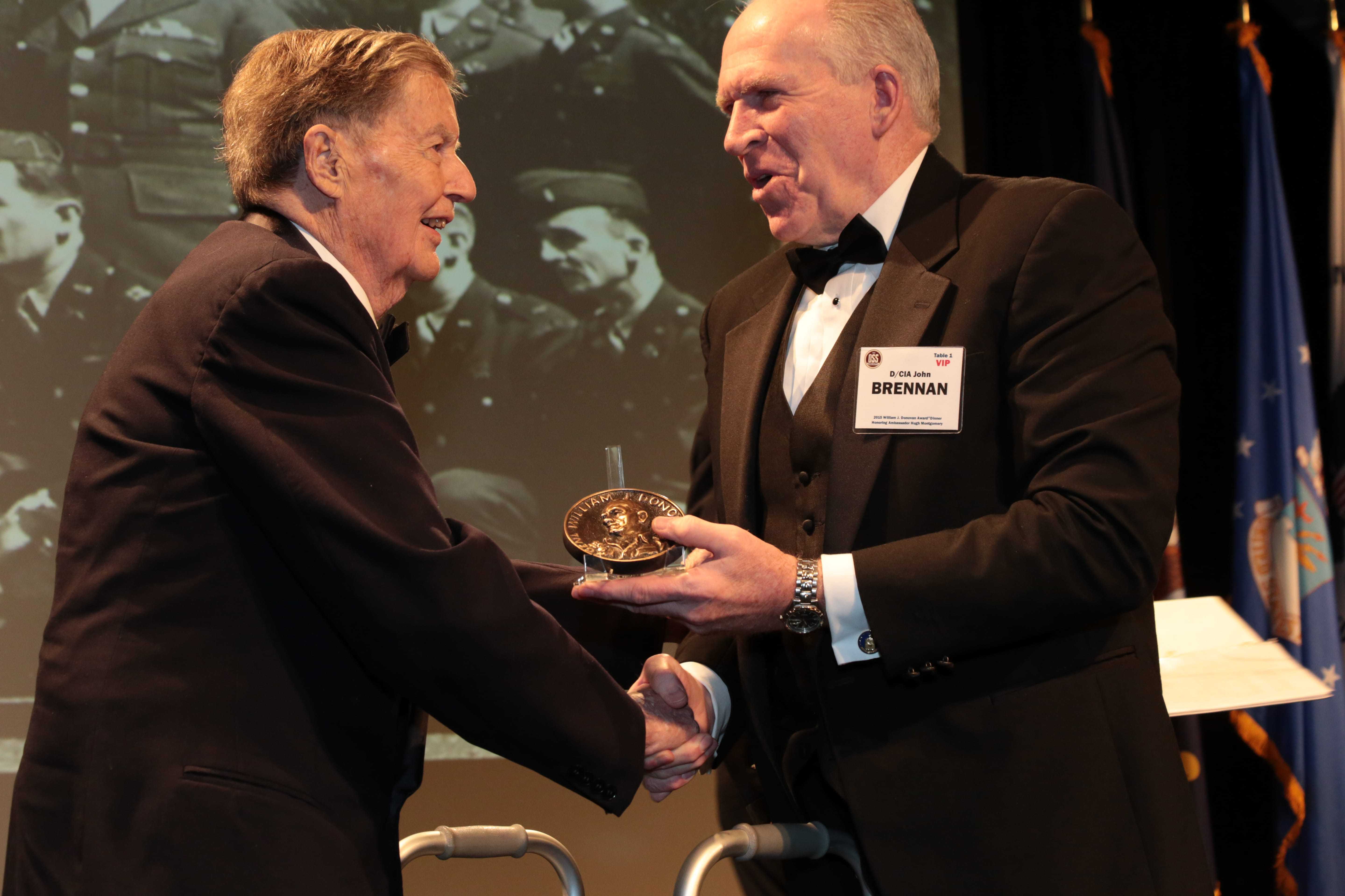 Ambassador Hugh Montgomery holding the Donovan Award, standing next to former CIA Director Brennan.