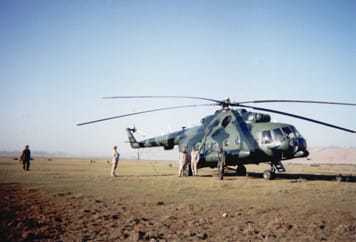A helicopter landed on a large flat area, surrounded by several people.