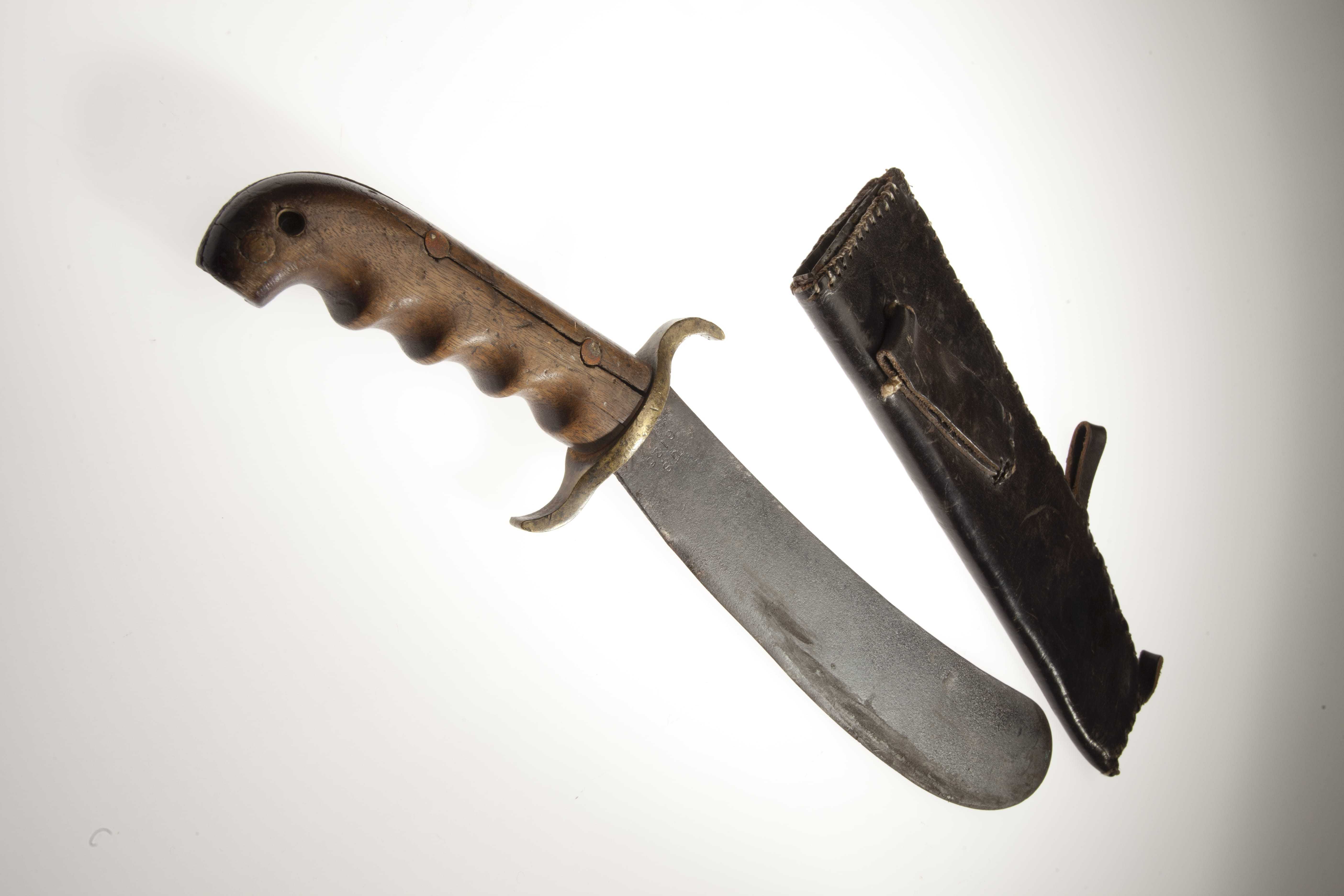 A flat, rounded knife with a wooden handle next to its leather sheath.