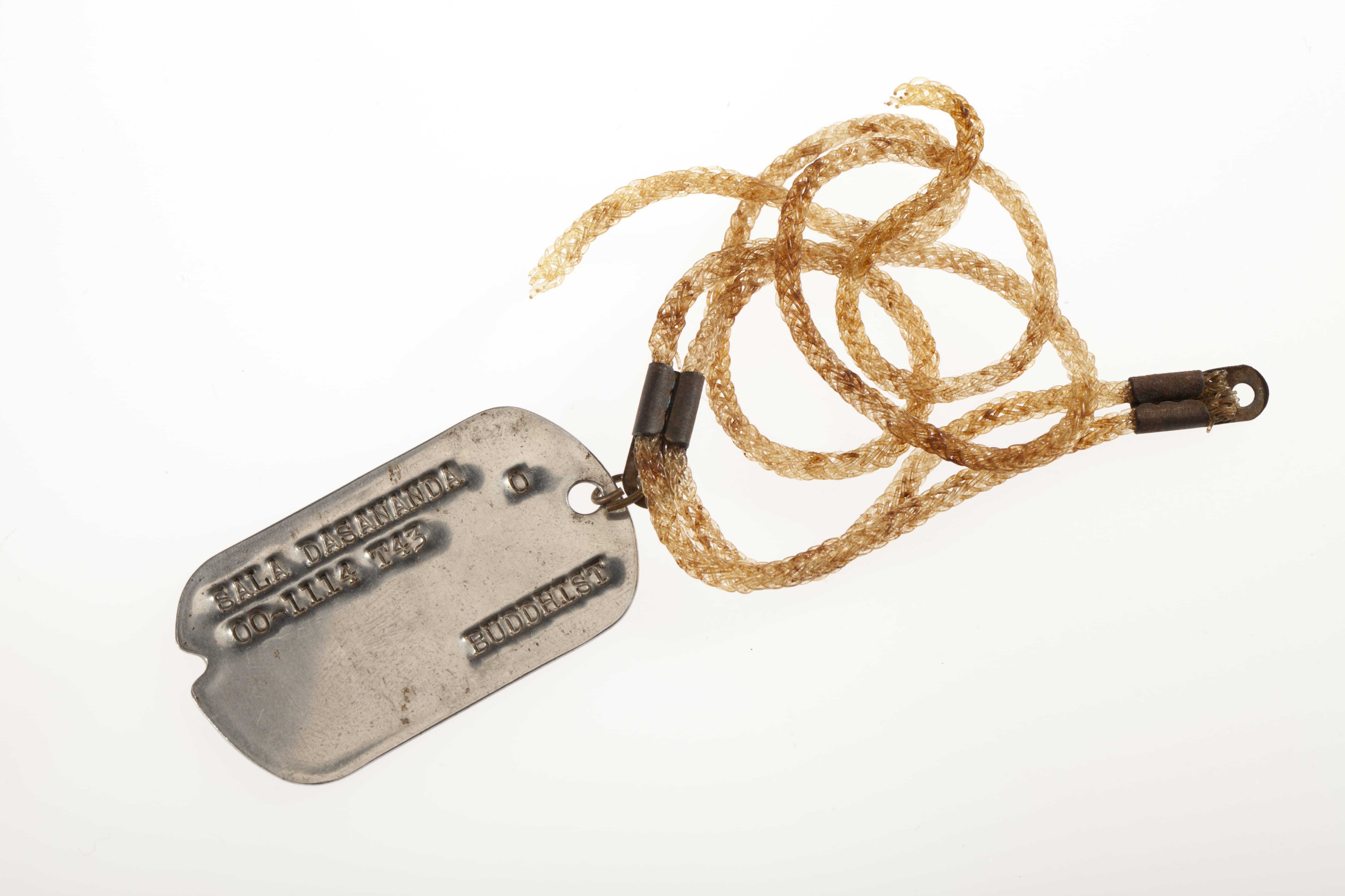 A dog tag with the name "Sala Dasanada", an ID number, and the word "Buddhist" engraved on it.