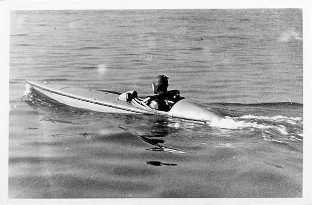 A person in a wetsuit piloting a submersible canoe.