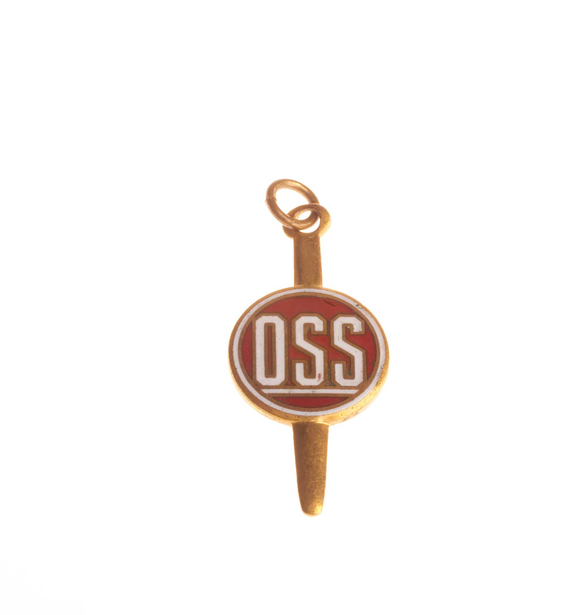 A gold pin with OSS written on a red circle in the middle