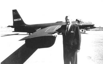 Man in suit standing beside a U-2 resting his arm on the wing.