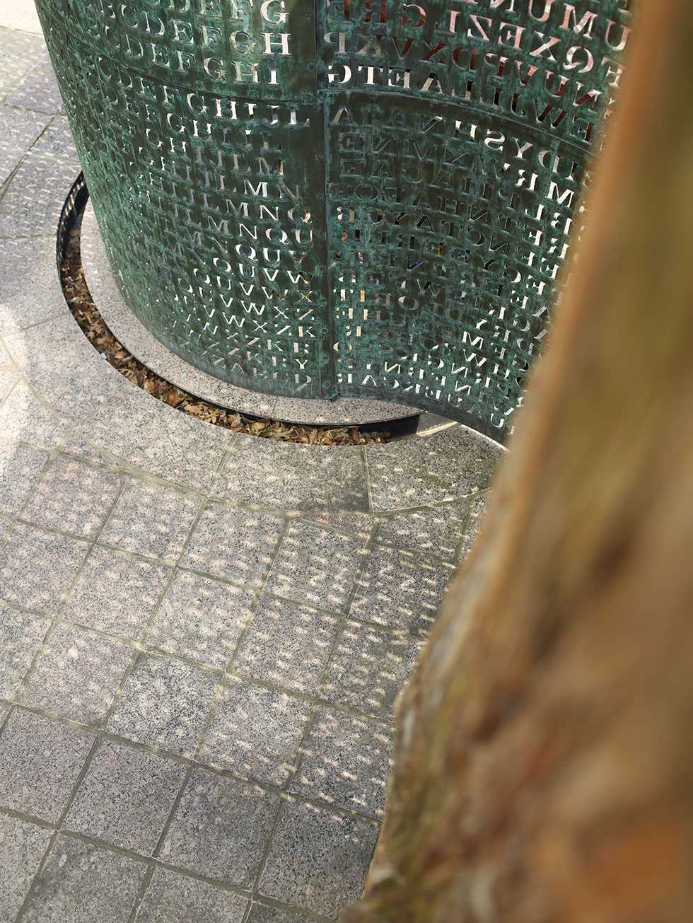 A shot looking downward at the base of the encircled copper screen with an indented ring in the ground collecting leaves and rainwater.