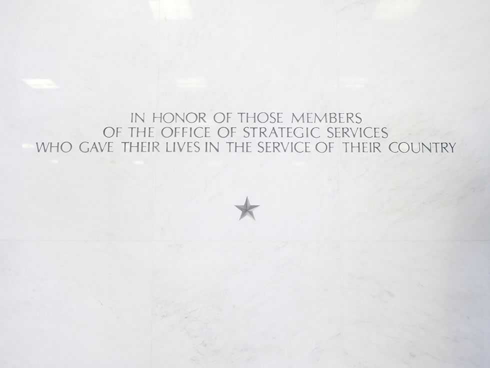 A close up of an inscription engraved on a white wall with a star underneath.