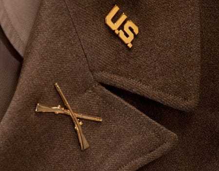 A close up view of two gold pins on the lapel of the uniform jacket.