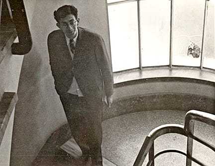 A black and white photograph of James Angleton walking down stairs.