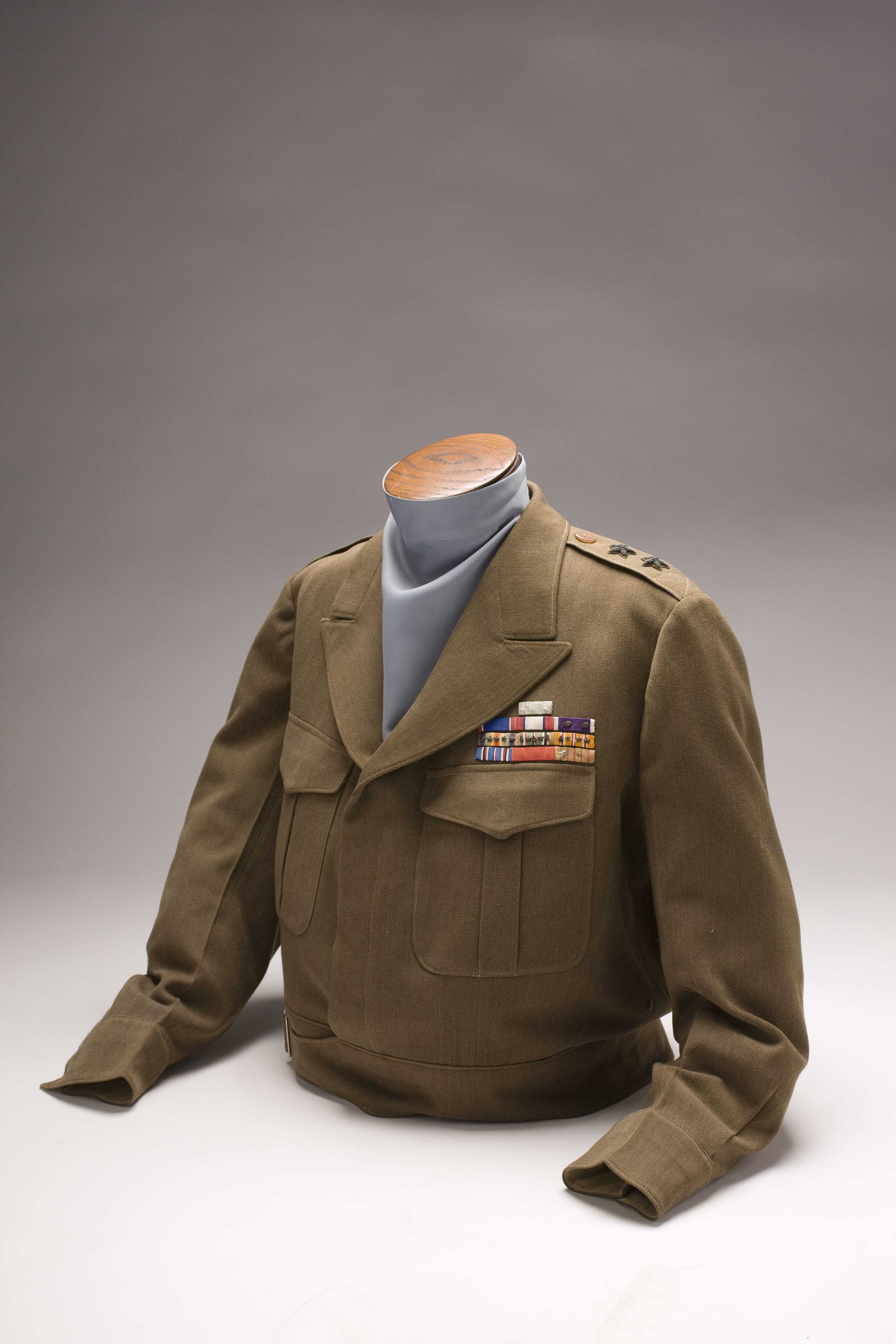 A green military-style jacket with pins lining the upper right pocket