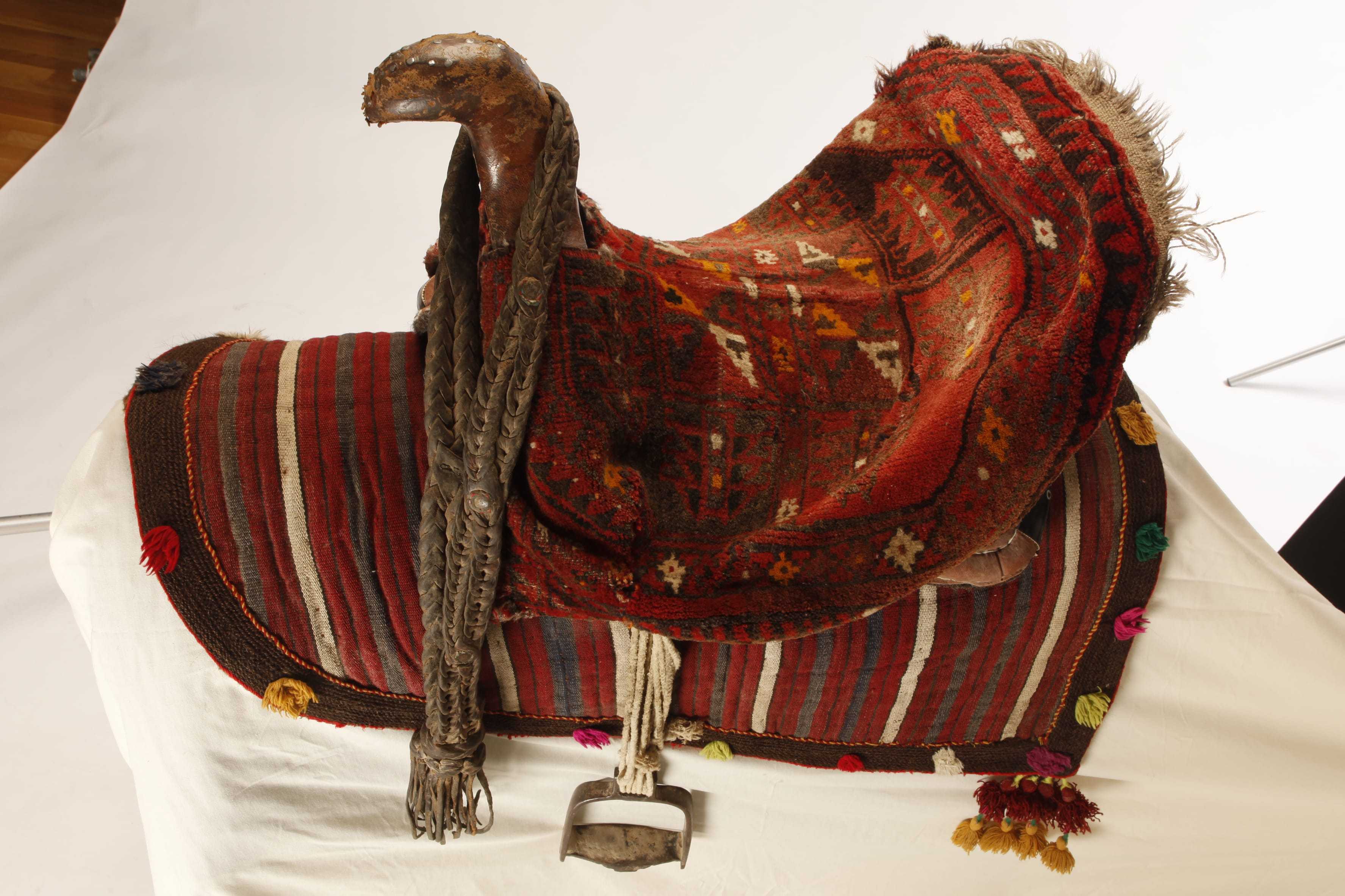A saddle decorated with red woven cloth and tassels