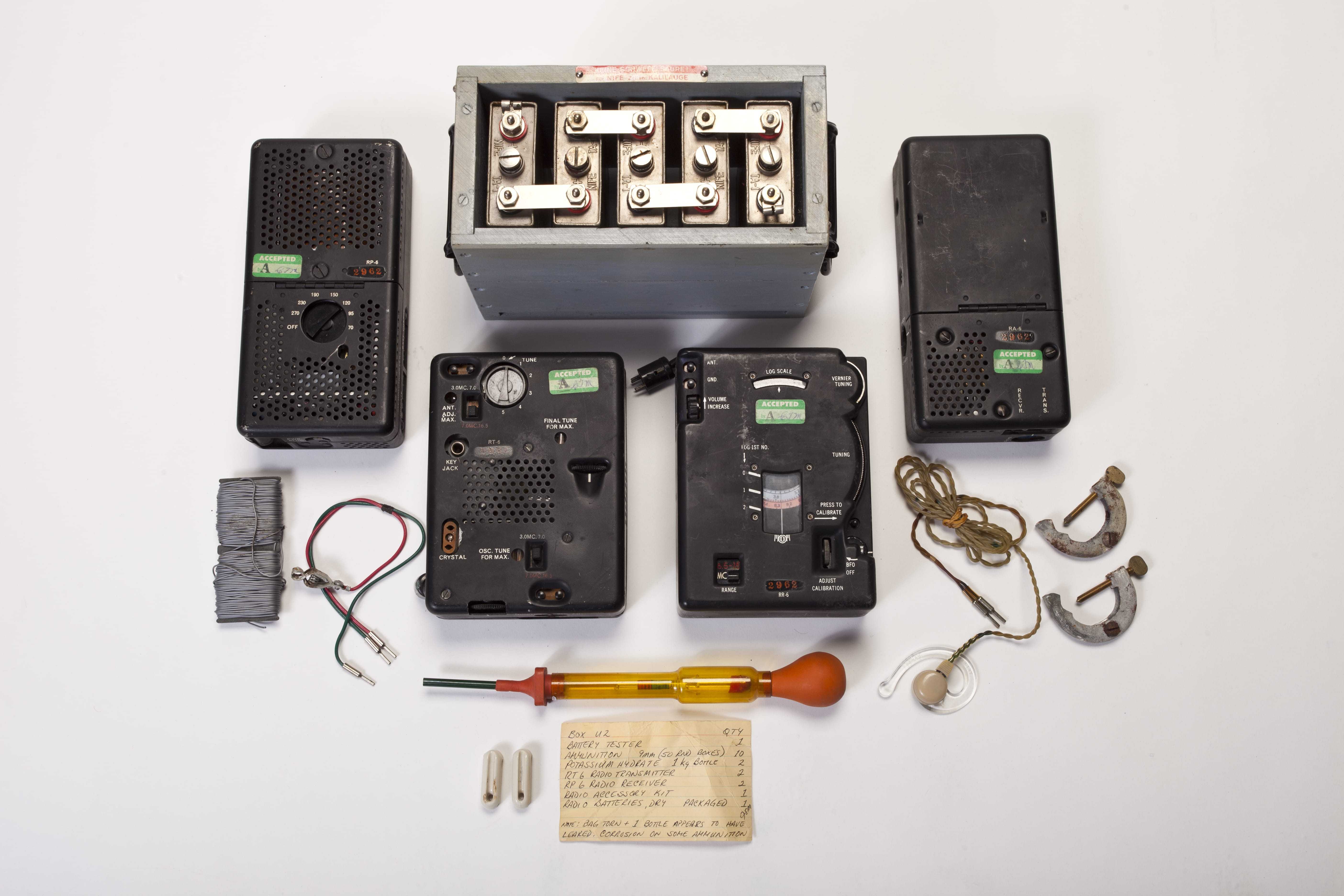 A set of four radios and speakers, surrounded by wires and other instruments to power the radio.