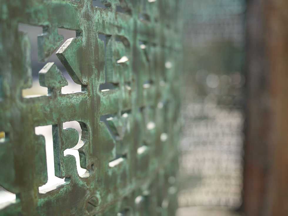 An up-close shot of the letters K and R inscribed in the copper screen with a blurred background.