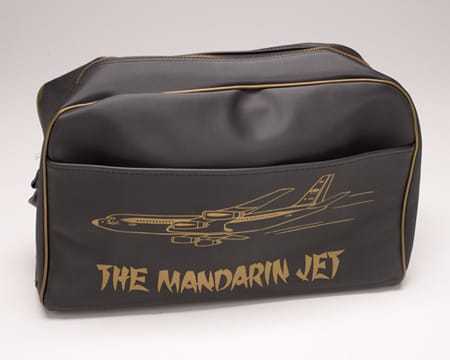 'The backside of a black zippered bag with "The Mandarin Jet" printed in gold