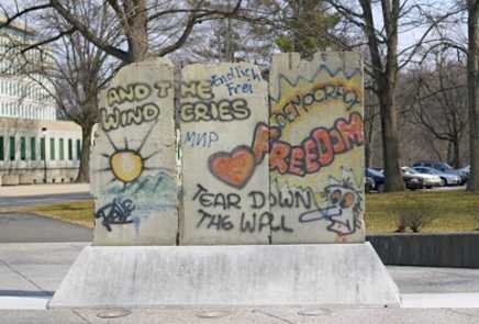 A wide view of three segments from the Berlin Wall, mounted on top of a granite display stand.