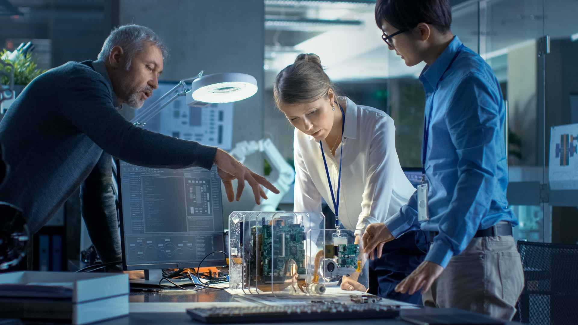 Three professionals standing around a complex mechanical device on a table.