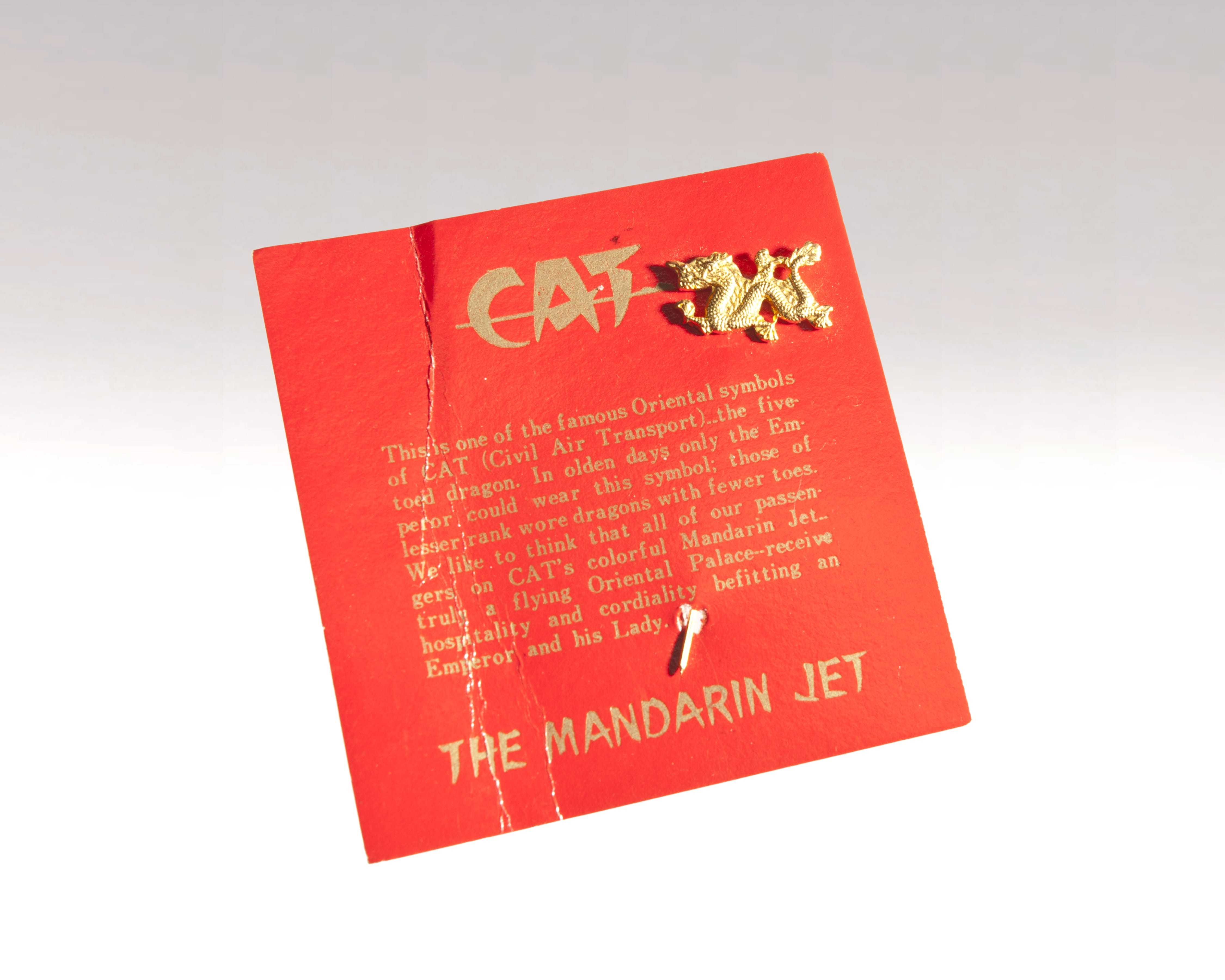 A five-toed dragon pin attached to a red card with the Civil Air Transport logo