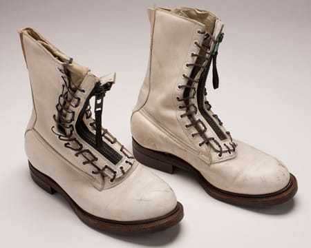 A pair of tall white boots with laces and zippers