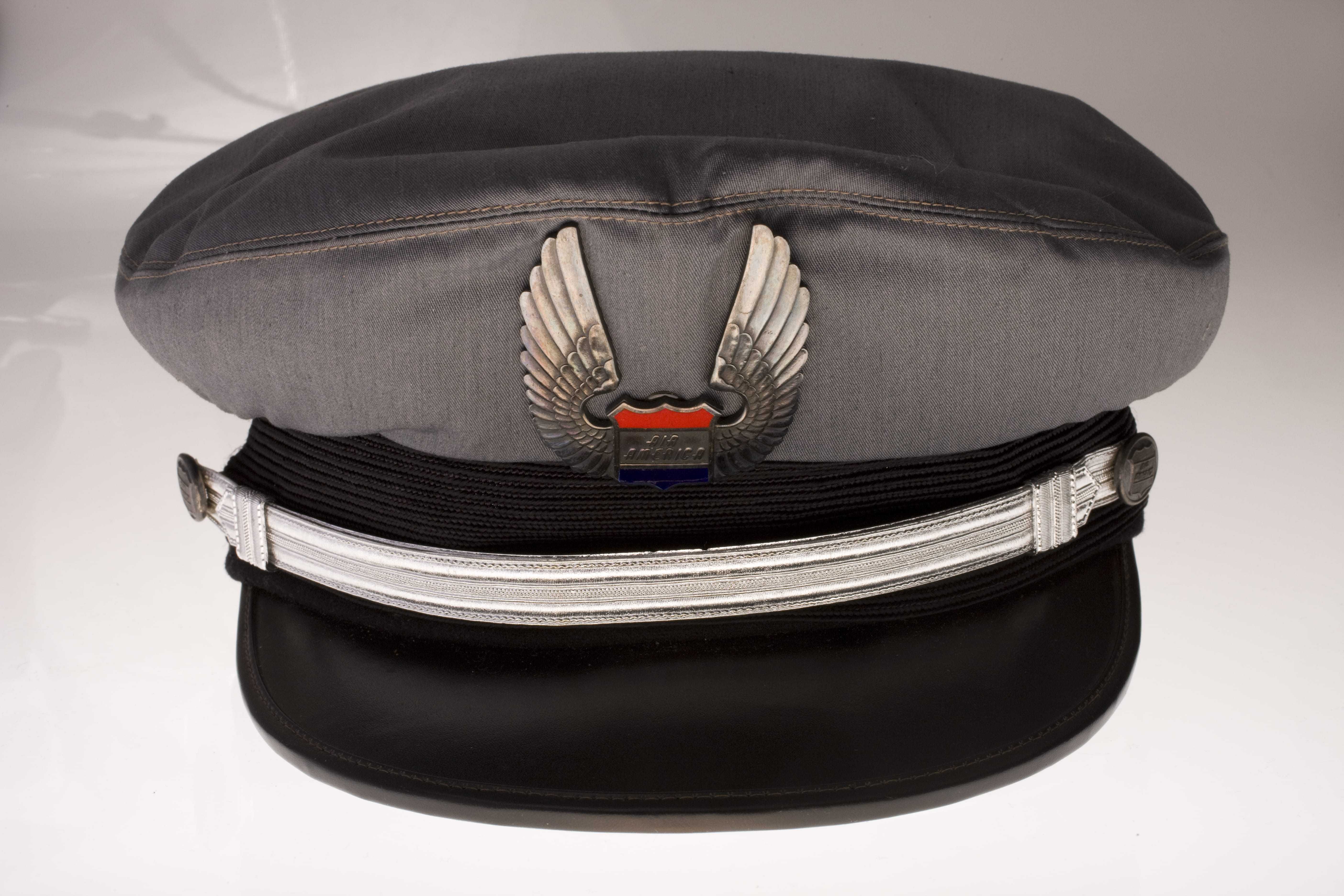 A pilot's cap with a metal Air America logo pinned to the front