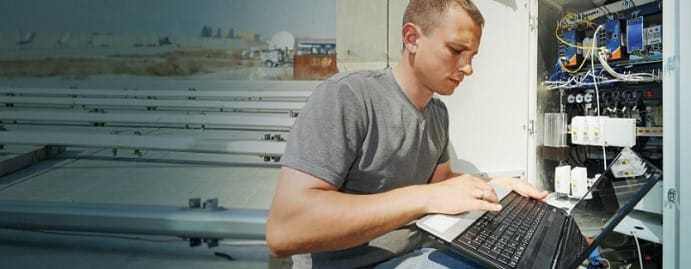 A young man using his laptop in the field.