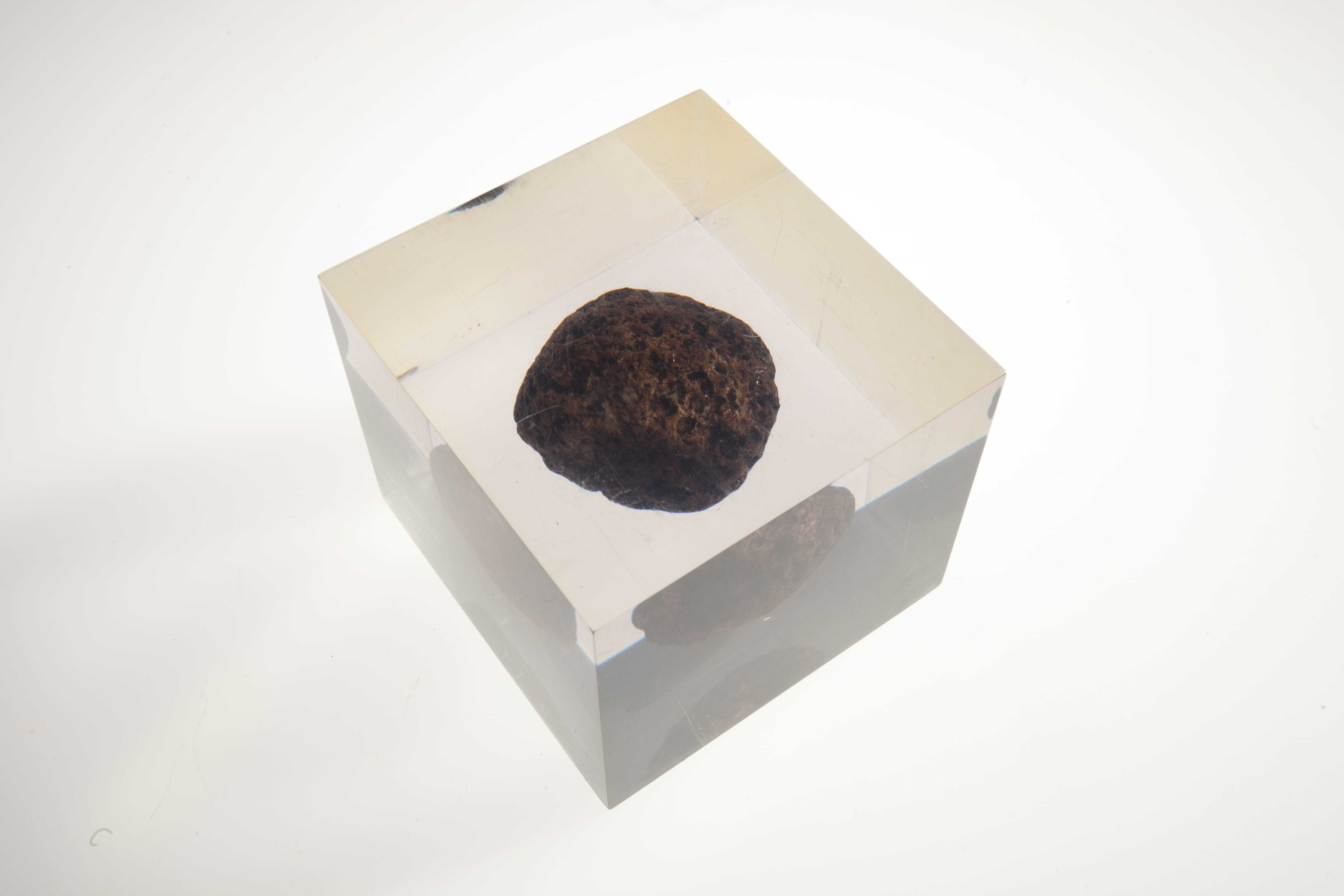 A brownish lump of Manganese encased in a glass block.