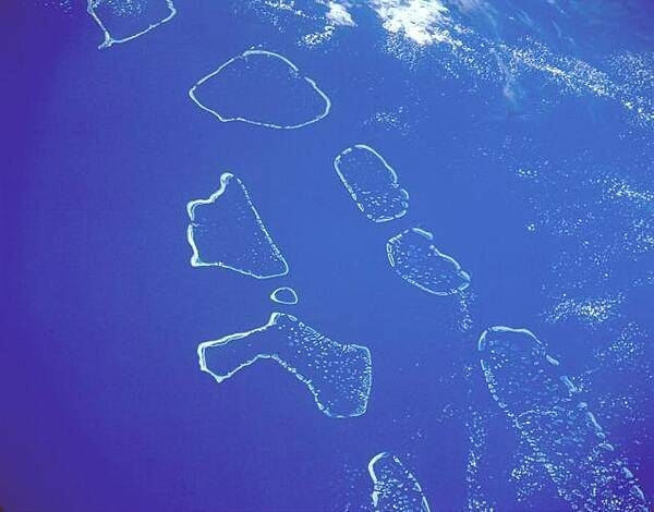 This south-looking, low-oblique photograph shows (from north to south) the Ari, Male, Felidu, Nilande, Mulaku, and Kolumadulu Atolls of the Maldives. The 26 atolls of the Maldives are composed of 1,190 small coral islands. The island chain extends north-south for approximately 880 km (550 mi). The Maldives are the exposed top of a long, narrow submarine ridge whose average height is 1 to 2 m (3 to 6 ft) above sea level. Most of the atolls have spacious, deep-water lagoons suitable for ship anchorage. Image courtesy of NASA.