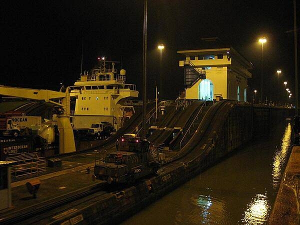 A view of the Panama Canal at night, including one of the locks buildings and a &quot;mule,&quot; one of the trains that pull ships through the locks.