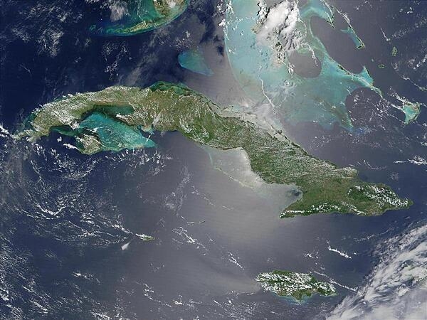 Satellite image of Cuba (center) and Jamaica (lower right). The southern tip of Florida, the Florida Keys, and the Florida Strait appear at the top. The bright blue-green color around the islands, particularly around the Bahamas in the upper right, is likely due to the brighter solar reflection over the more shallow waters that surround the islands. Image courtesy of NASA.