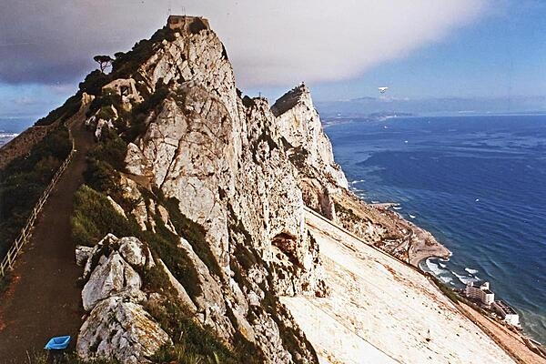 The Rock of Gibraltar is a monolithic limestone promontory (a raised mass of land that projects into a lowland or a body of water) that stands 426 m (1,398 ft ) high and is located in Gibraltar. The Rock is one of the two "pillars" flanking the Strait of Gibraltar; the other is located in northern Africa.