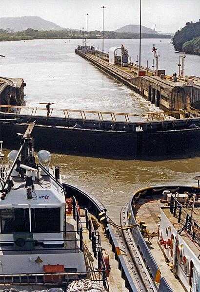 A view of a portion of the Panama Canal showing two tugs and lock gates.