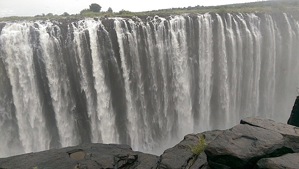 Victoria Falls is located between the borders of Zambia and Zimbabwe. During flood season (February to April), the falls form the greatest sheet of falling water on earth. Victoria Falls is 1.7 km (1.1 mi) wide and 108 m (360 ft) high and is known locally as Mosi-oa-Tunya (The Smoke that Thunders).  Victoria Falls became a UNESCO World Heritage site in 1989.