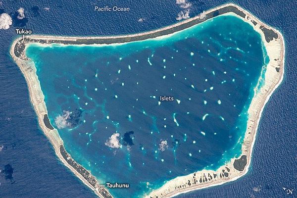 Manihiki is one of the larger islands, 10.5 km (6.5 mi) long, in the remote Cook Island chain. With its fringing coral reef and central lagoon, it has the hallmarks of a classic atoll. Most of the main atoll is made up of sandy beaches without vegetation. Two small towns -- Tauhunu and Tukao -- appear as clusters of small bright patches in the forest.  Image courtesy of NASA.