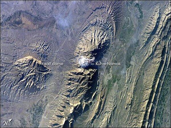 The Zagros Mountains in southwestern Iran present a landscape of long linear ridges and valleys. This astronaut photograph of the southwestern edge of the Zagros mountain belt includes another common feature of the region, a salt dome. Erosion has revealed the uplifted tan and brown rock layers surrounding the white salt dome to the northwest and southeast (center of image). Radial drainage patterns indicate another salt dome is located to the southwest (image left center). Image courtesy of NASA.