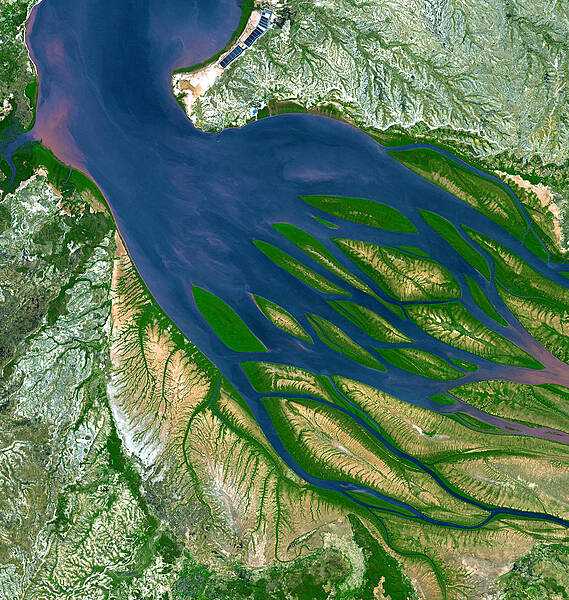 On the northwestern coast of Madagascar, the salty waters of the Mozambique Channel (top, north) penetrate inland to join with the freshwater outflow of the Betsiboka River  (right, east), forming Bombetoka Bay. Numerous islands and sandbars have formed in the estuary from the large amount of sediment carried in by the Betsiboka River and have been shaped by the flow of the river and the push and pull of tides. Image courtesy of NASA.