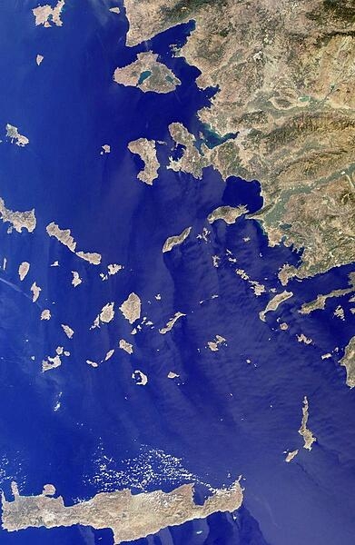 This image includes many of the islands of the East Aegean, as well as part of mainland Turkey. The largest modern city in the Aegean coast is Izmir, Turkey, situated about one quarter of the image length from the top. The city is the bright coastal area near the greenish waters of Izmir Bay and southeast of the roughly triangular-shaped island of Lesvos. The lengthy island at the bottom of the photo is Crete. North of Crete, the small broken ring of islands are the remnants of the collapsed caldera of Santorini Volcano. Image courtesy of NASA.