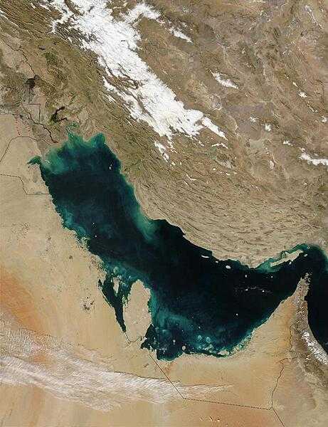 Much of the sediment clouding the water in this image of the Persian Gulf is from the Shatt al Arab River, which enters the Gulf in the north along the Iran-Iraq border. On the right edge of the image is the narrow Strait of Hormuz, which connects the Persian Gulf to the Arabian Sea. The Persian Gulf is flanked to the west by wedge-shaped Kuwait and by Saudi Arabia with its vast tan-, pink-, and white-sand deserts; to the south by Qatar, the United Arab Emirates, and Oman; and to the east by the dry mountains of Iran. The red dots mark gas flares in oil fields of Iran and Iraq. Image courtesy of NASA.