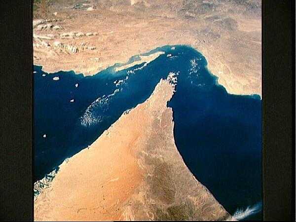 This oblique, north-looking view shows the Strait of Hormuz, which connects the Gulf of Oman (on the right) with the Persian Gulf (on the left). The Zagros Mountains and Qeshm Island of Iran are in the background and areas of Oman, Muscat, and the United Arab Emirates may be seen in the foreground. The oil tanker terminals of Abu Dhabi along the southern coast of the Persian Gulf can also be clearly seen along the northern United Arab Emirate coastline (lower left). Image courtesy of NASA.