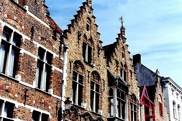 Weather vanes, tall windows, and distinctive roof lines along a canal in Bruges (or Brugge), Belgium.