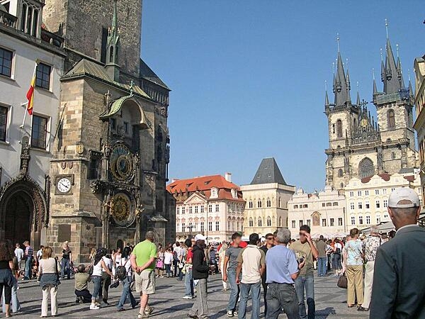 A view of a section of the Old Town Square in Prague, Czechia. The medieval astronomical clock on the Old Town City Hall dates to 1410. In the background is Tyn Cathedral, one of the oldest churches in Prague, whose construction began in the 14th century.