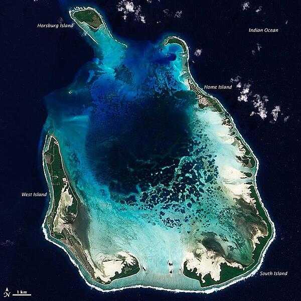 The Cocos (Keeling) Islands lie in the eastern Indian Ocean, about 2,900 km (1,800 mi) northwest of the Australian city of Perth. This natural-color satellite image of the South Keeling Islands was taken in July 2009. Along the southern rim of this coral atoll, the shallow water appears aquamarine. The water darkens to navy blue as it deepens toward the central lagoon. Above the water line, coconut palms and other plants form a thick carpet of vegetation. Image courtesy of NASA.