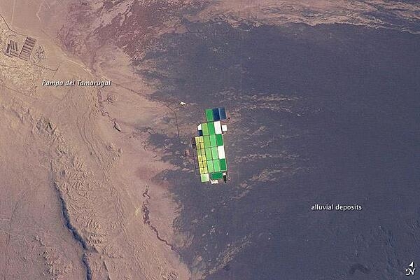 Brightly colored solar-evaporation (salt) ponds in a desert landscape give this astronaut photo an unreal quality. The ponds sit near the foot of a long alluvial fan in the Pampa del Tamarugal, the hyper-arid inner valley of Chile's Atacama Desert. The alluvial fan sediments are dark brown, and they contrast sharply with the Pampa del Tamarugal's tan sediments. Nitrates and many other minerals are mined in this region, and a few extraction pits and ore dumps are visible in the upper left. Image courtesy of NASA.